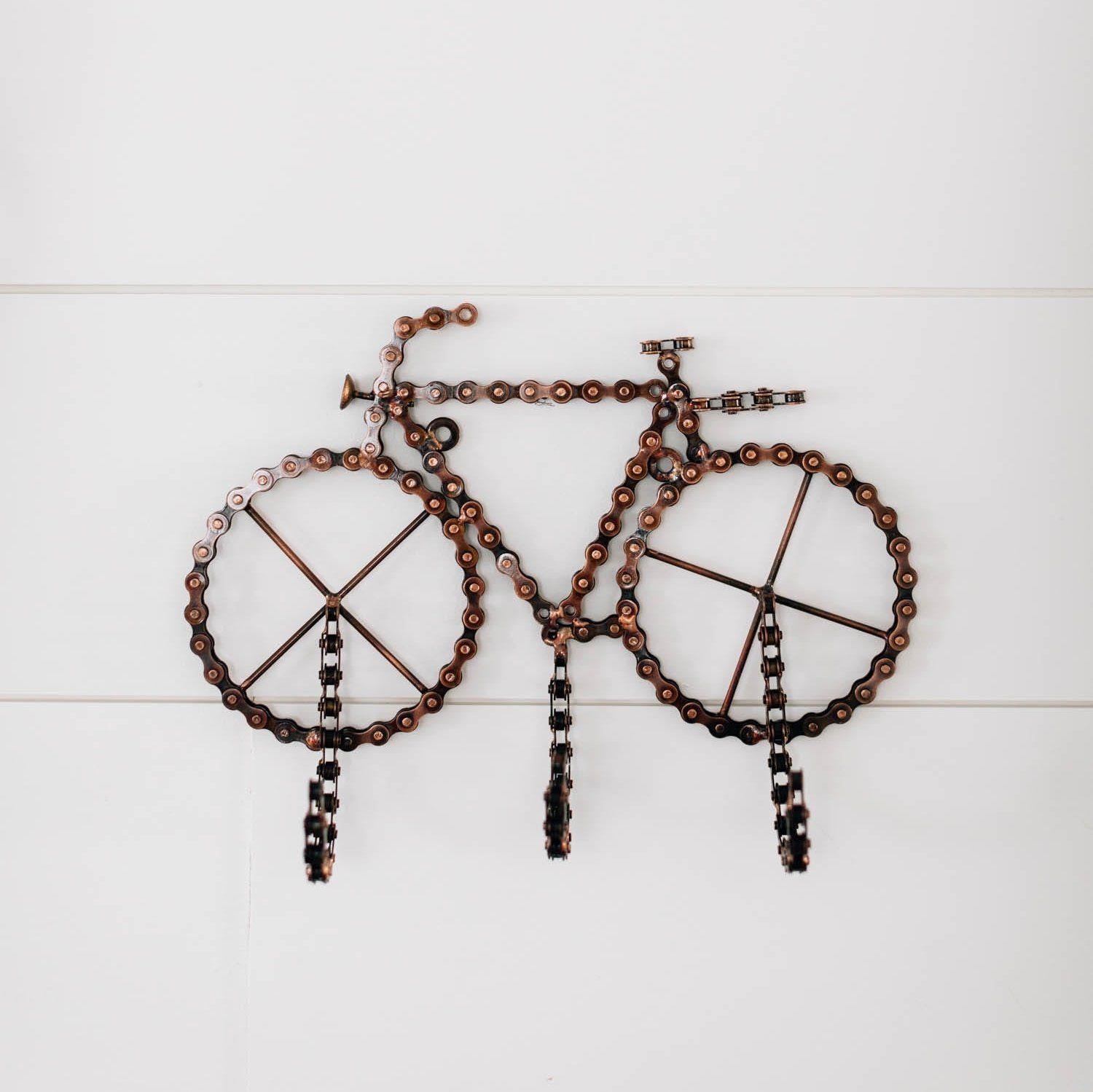 Handcrafted bicycle wall hook made from recycled bike chain hanging on garage wall