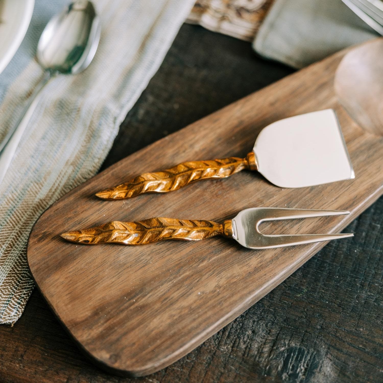 Elegant Feather Cheese Knife Set displayed on a wooden cheese board, showcasing the brass handles.