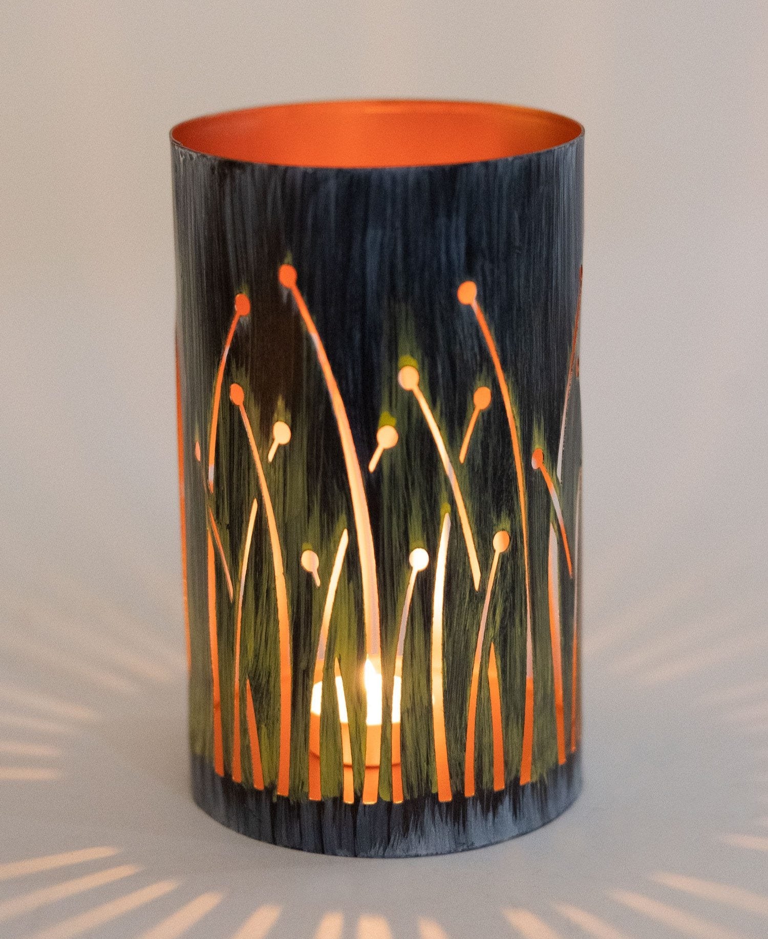 Close-up of handcrafted seagrass design on iron candleholder with copper interior