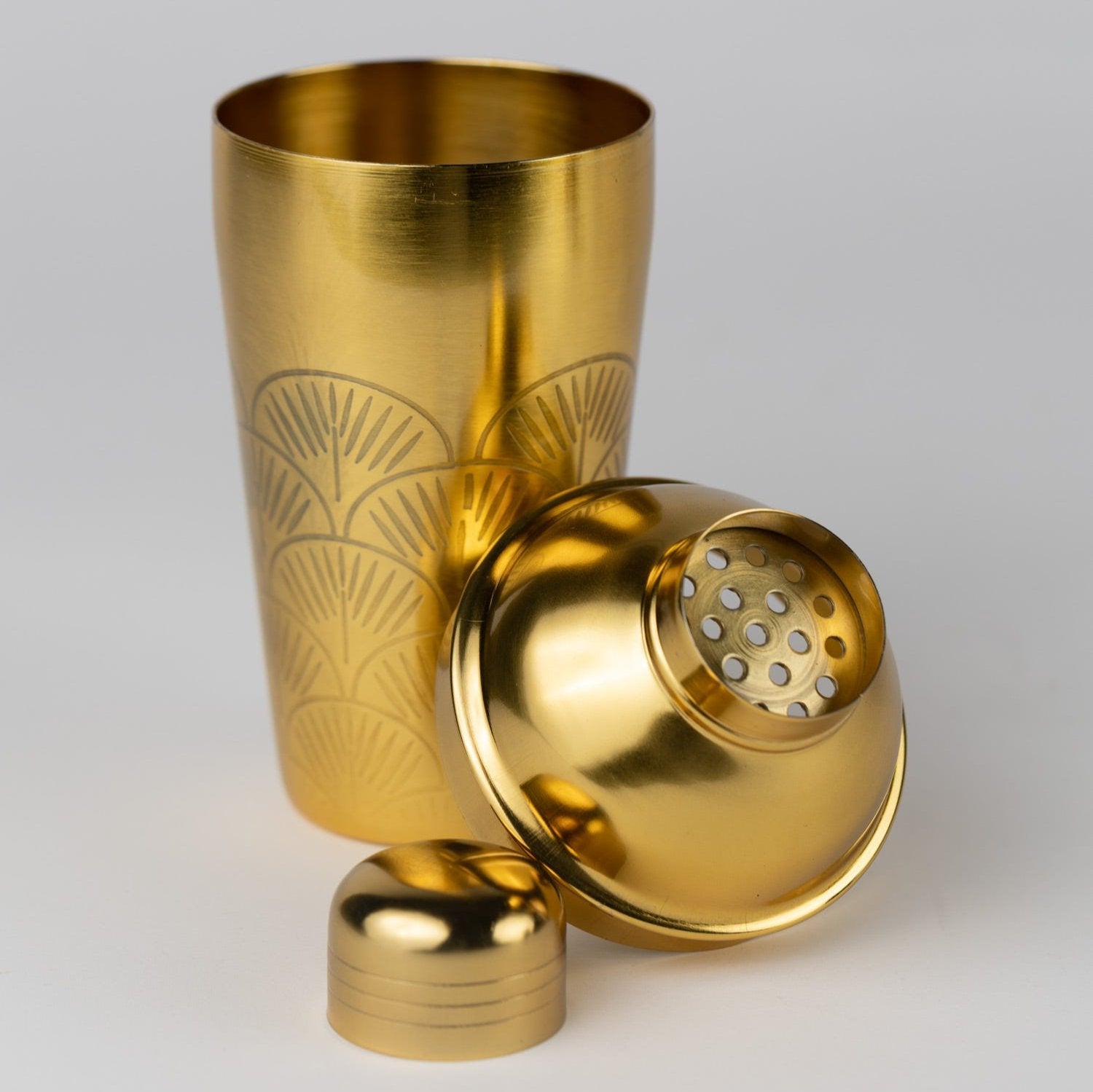 Close-up of handcrafted brass cocktail shaker with strainer and fan design