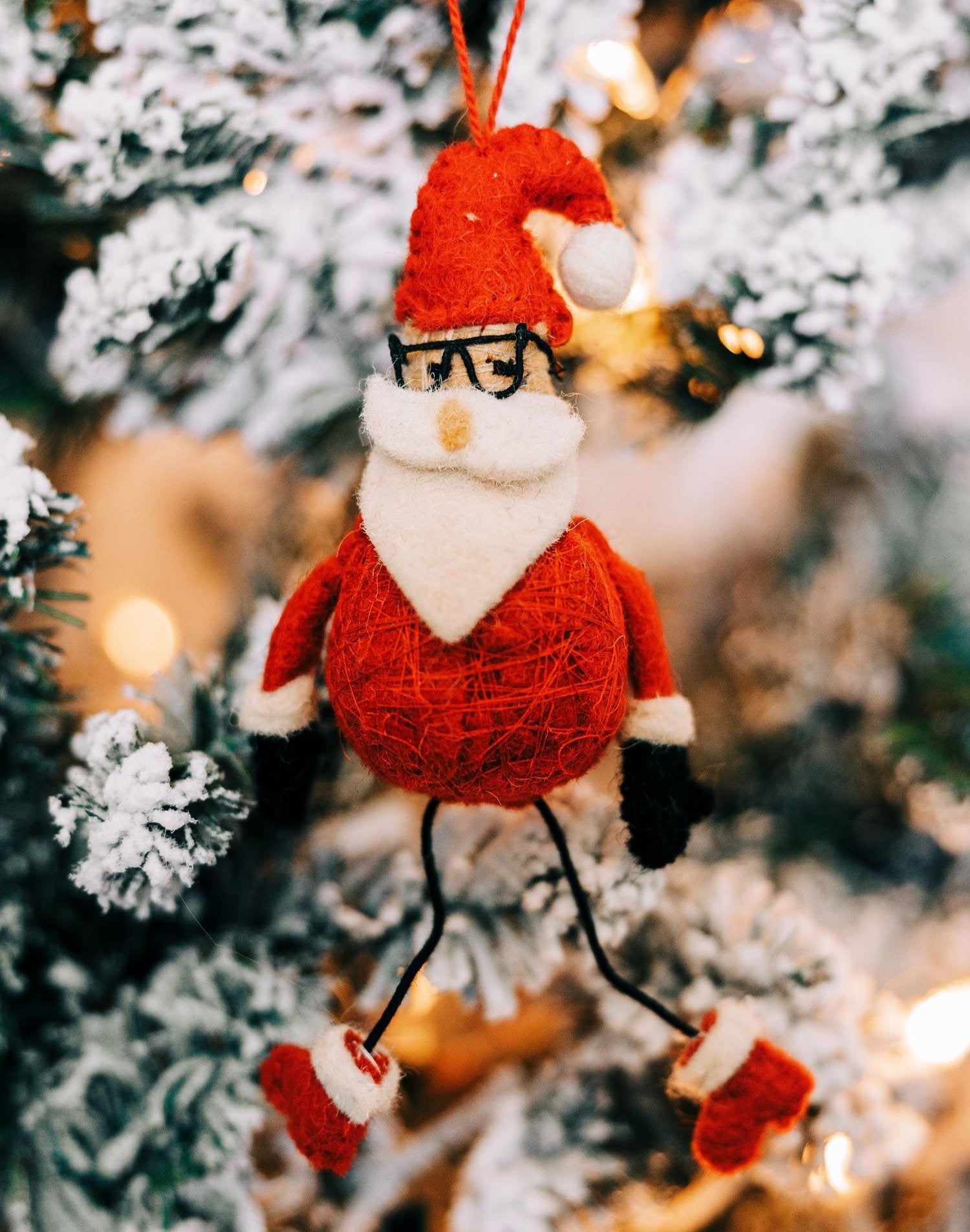Flexible Santa Claus Ornament hanging on a Christmas tree, showcasing its posable legs and festive colors.