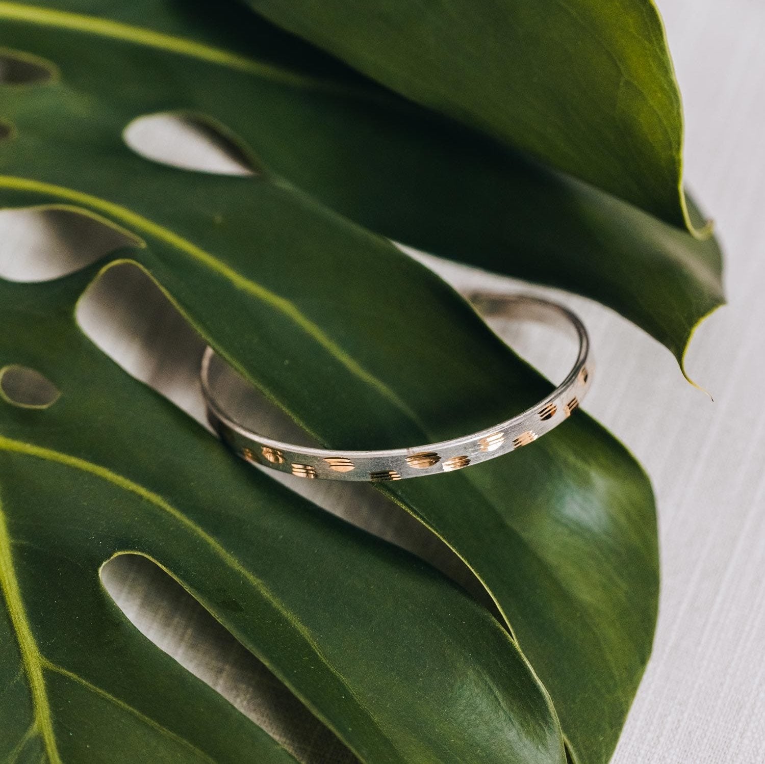 Close-up of Mythic Mark cuff bracelet showing silver and brass details