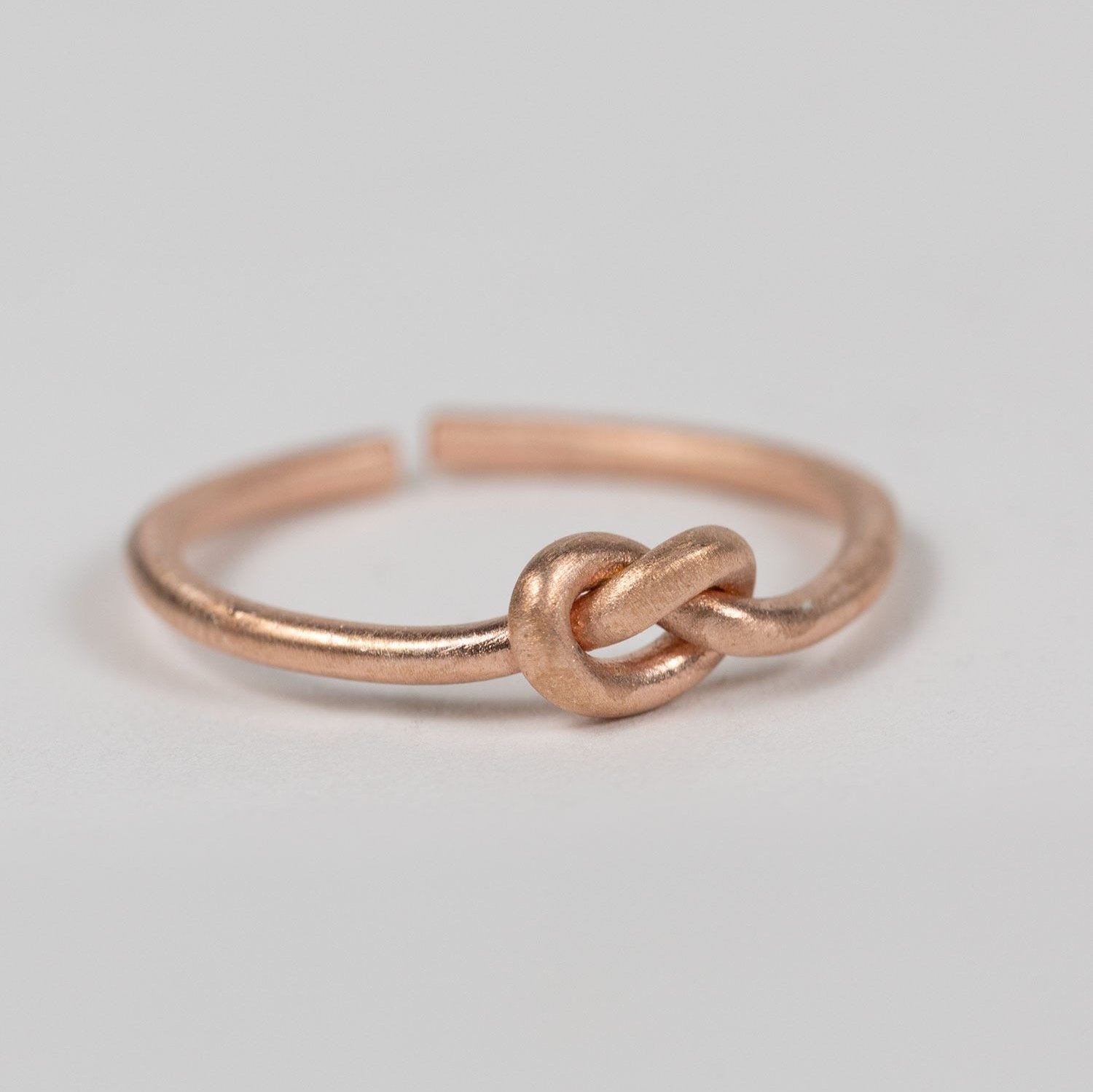 Front view of a handcrafted rose gold brass knot ring highlighting the simple knot design
