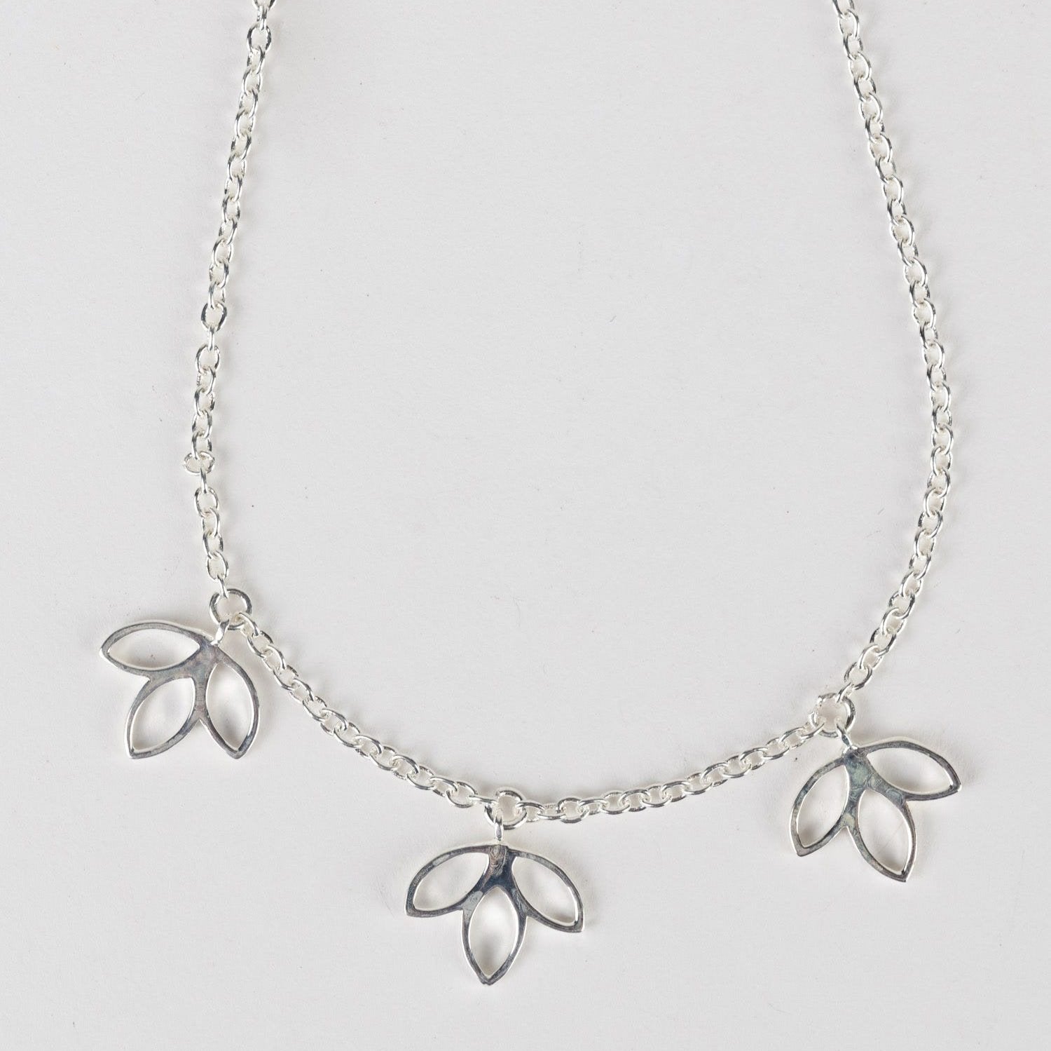 A close-up of a beautifully handcrafted lotus flower necklace on a delicate chain.
