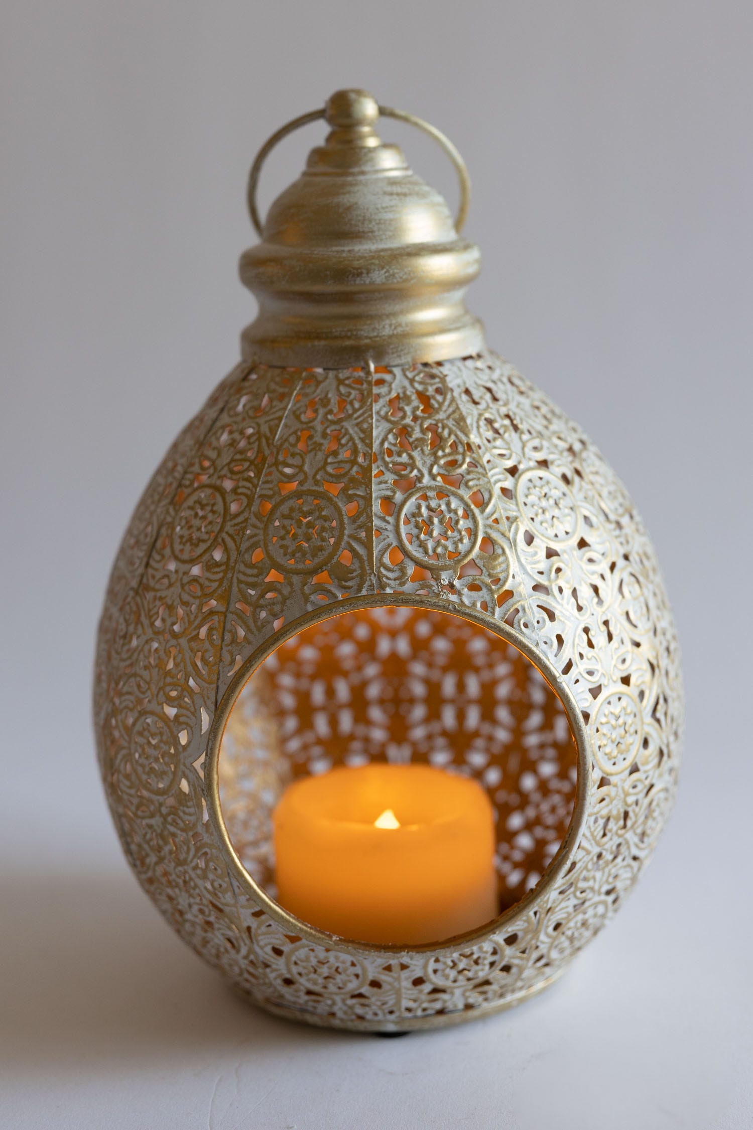 Radiant teardrop hanging lantern showcasing intricate metalwork against a bright background.