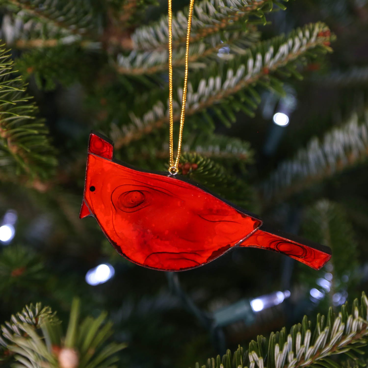 Cardinal ornament hanging in sunny window, radiating soft crimson glow