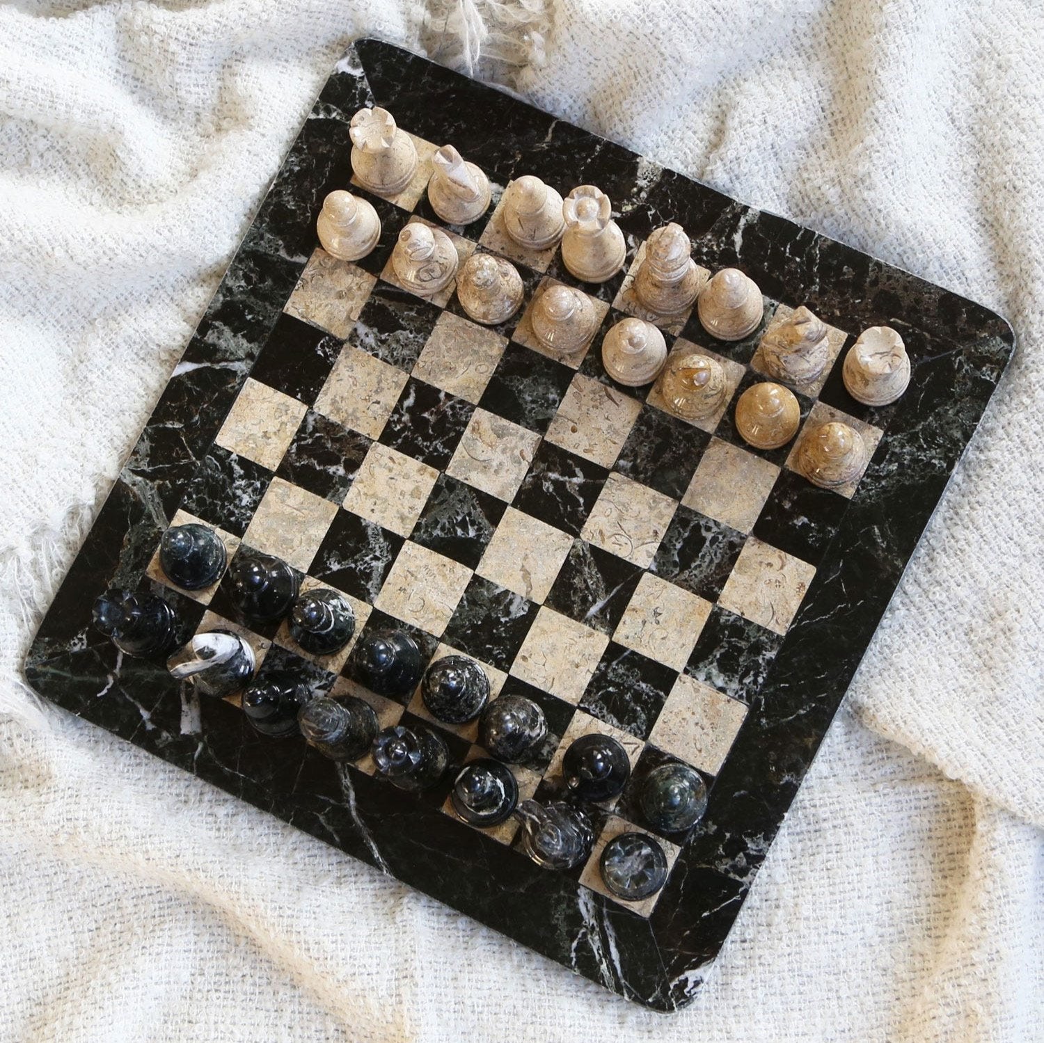 Close-up of handcrafted black and tan chess pieces made from zebra and coral stones