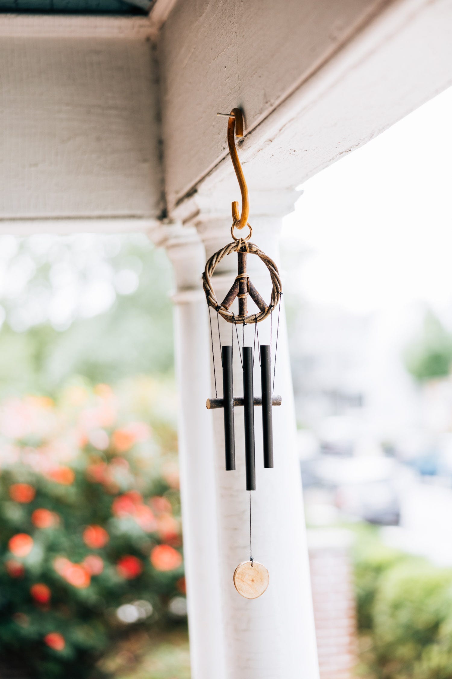 Close-up of peace sign wind chime with black metal chimes hanging outdoors