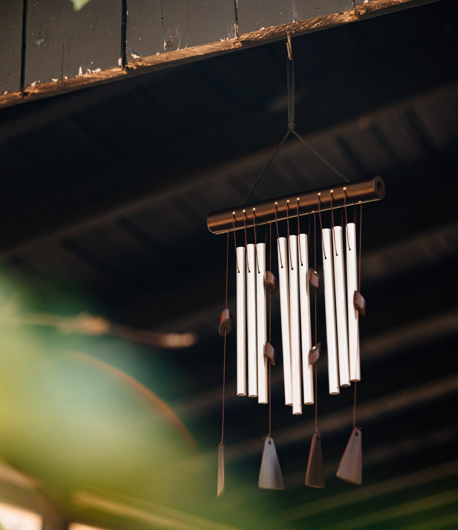 Close-up of handcrafted bamboo wind chime with metal tubes hanging outdoors