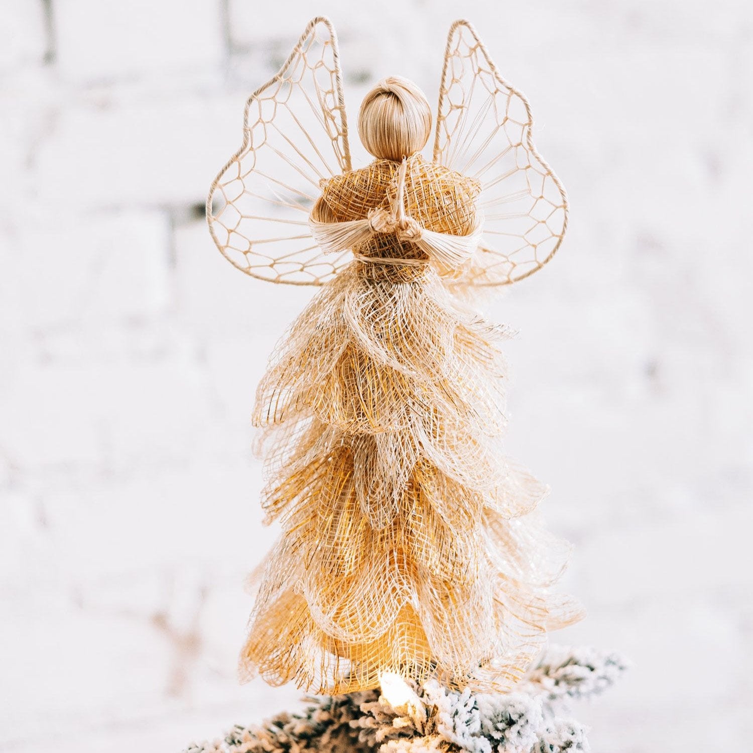 Close-up of a handcrafted golden angel sinamay topper on Christmas tree