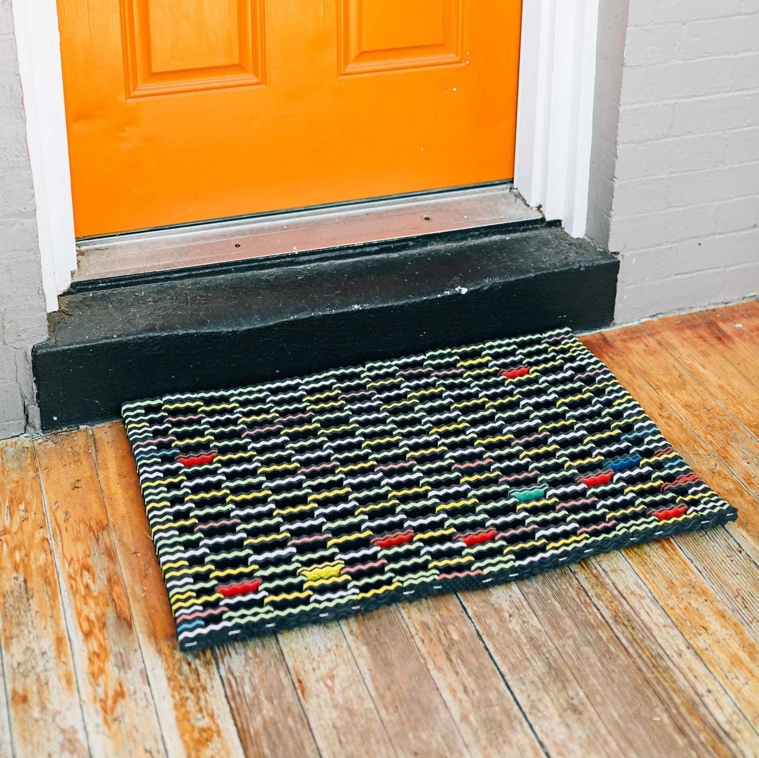Vibrant upcycled flip-flop mat placed at the entryway, showcasing its colorful design.