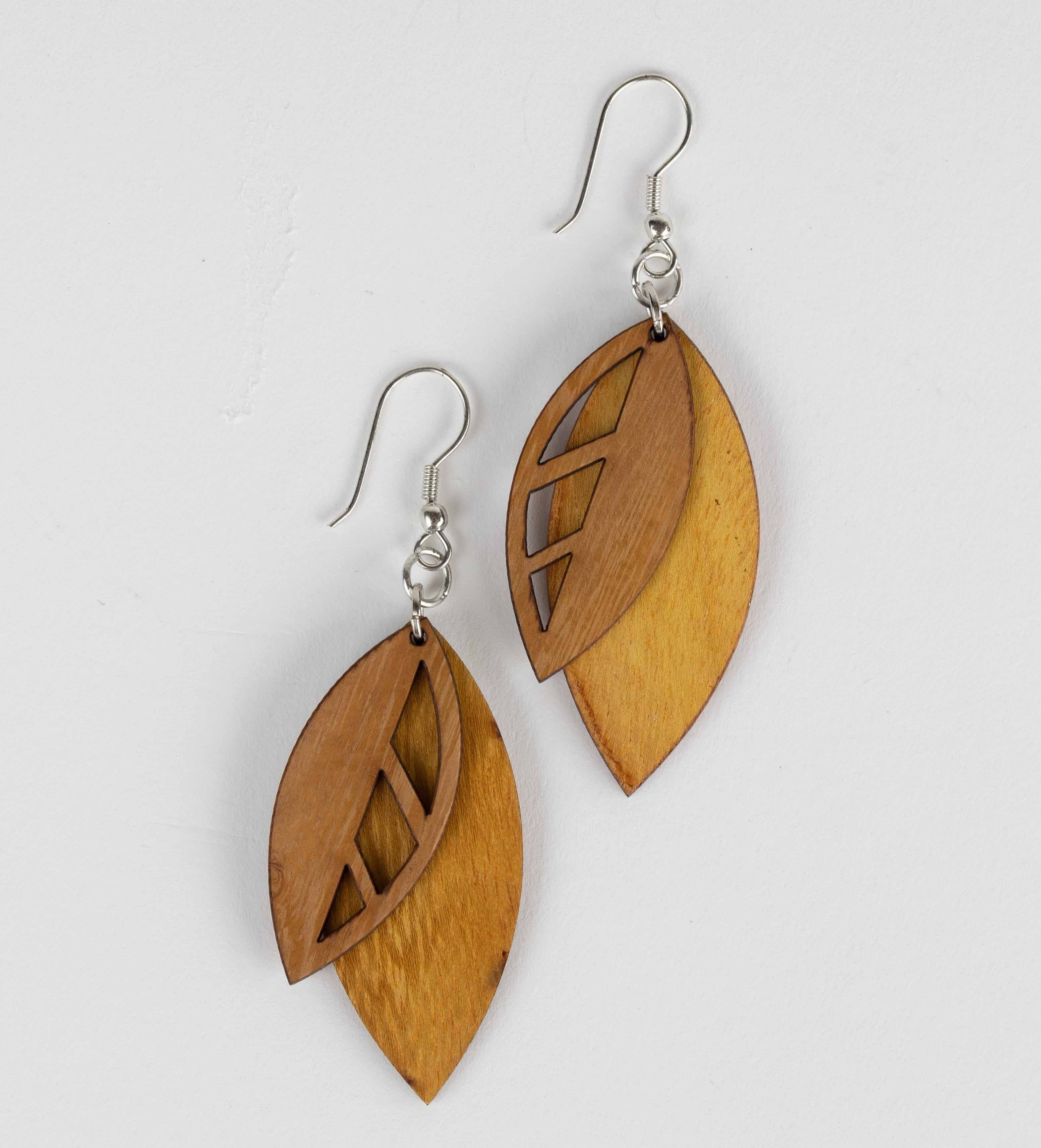 Close-up of handcrafted wooden leaf earrings with detailed grain and natural finish