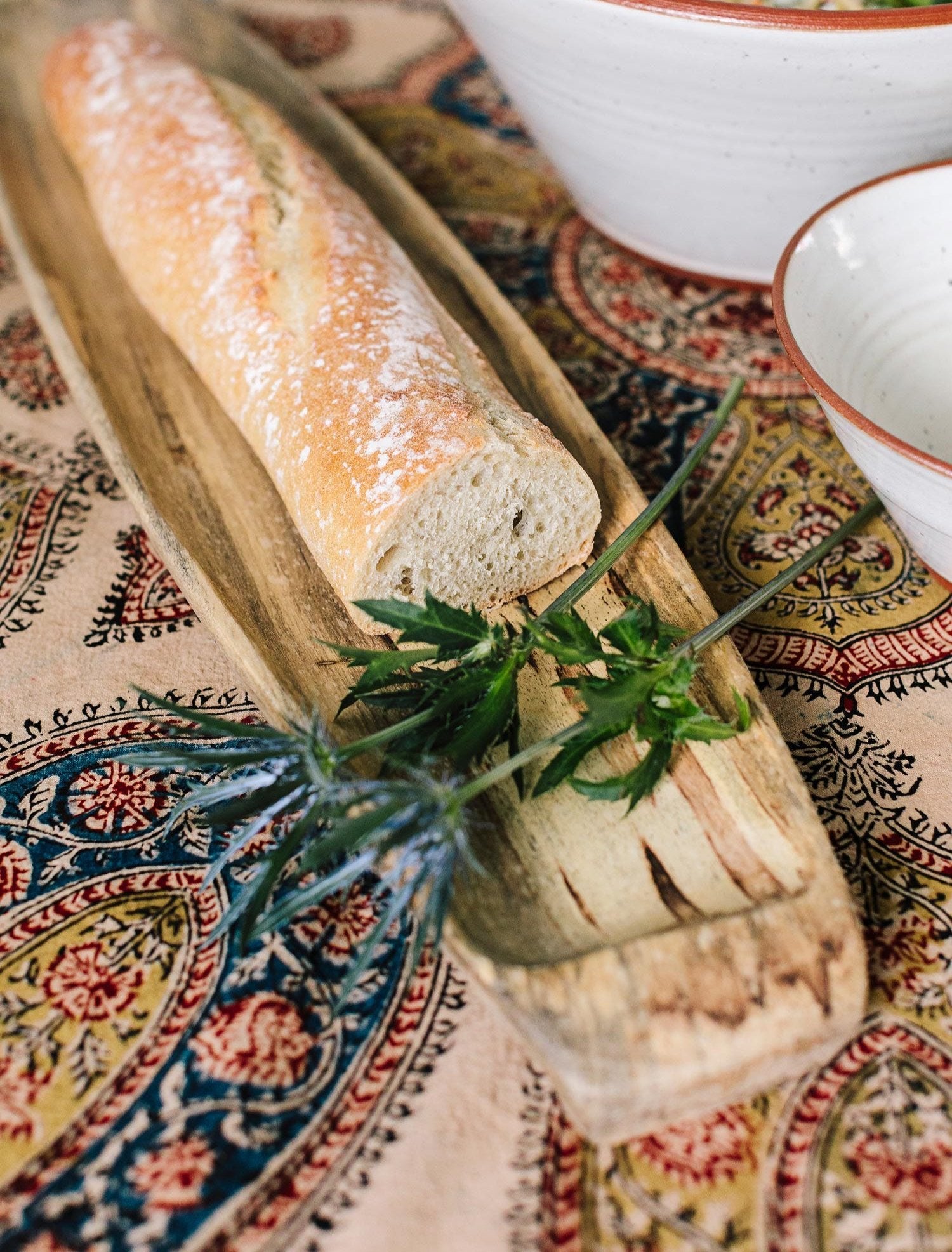 Artisan French bread serving tray with fresh baguettes and butter on a dining table.