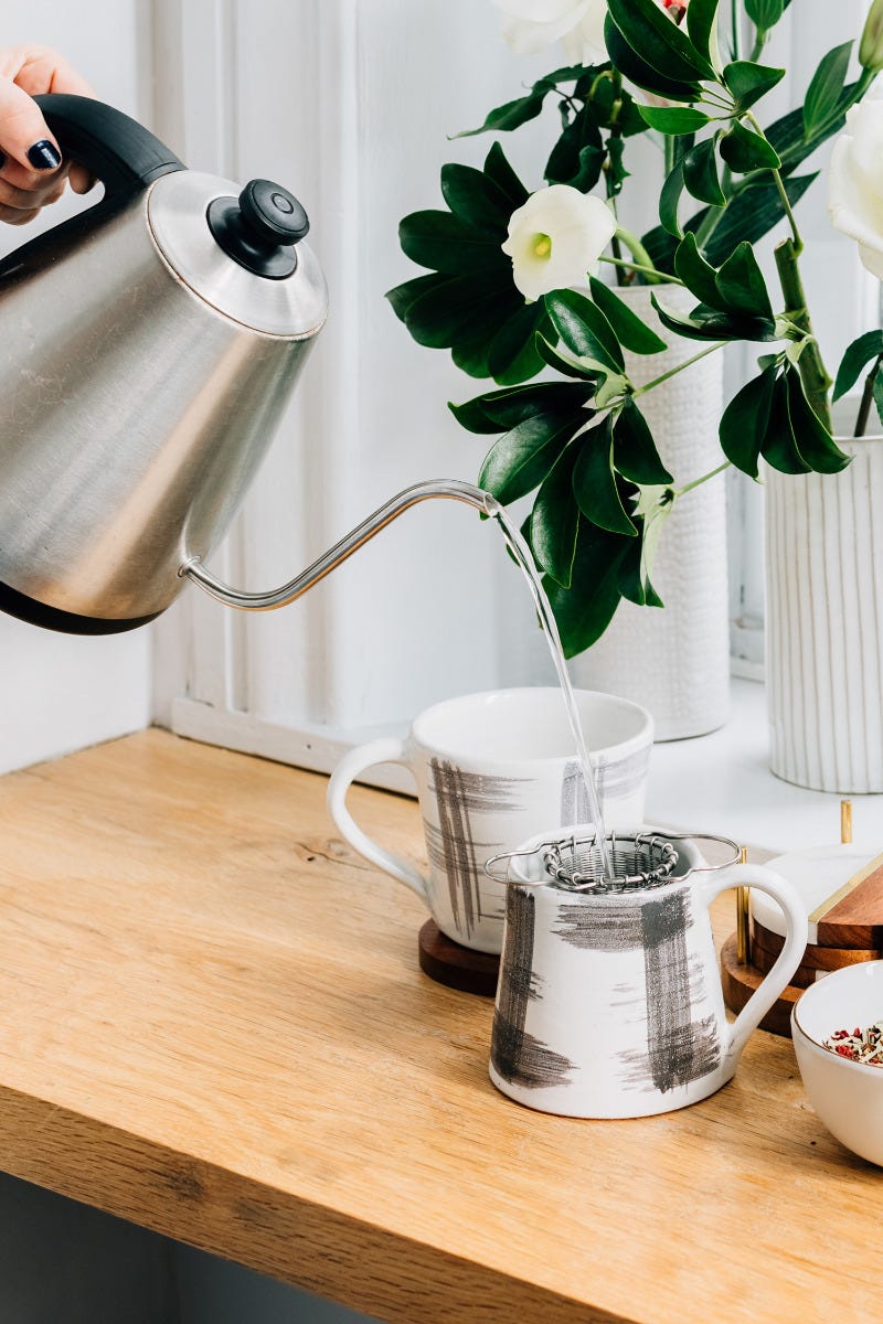 Lifestyle shot of the coffee mug placed on a wooden table alongside fresh-brewed coffee