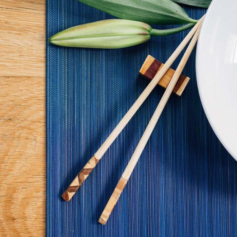 Top view of handcrafted chopsticks and geometric rest placed on linen napkin – fair trade kitchenware