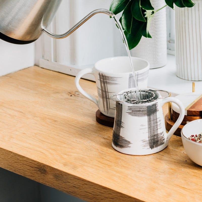 Reusable tea strainer in use with loose-leaf tea on a wooden table